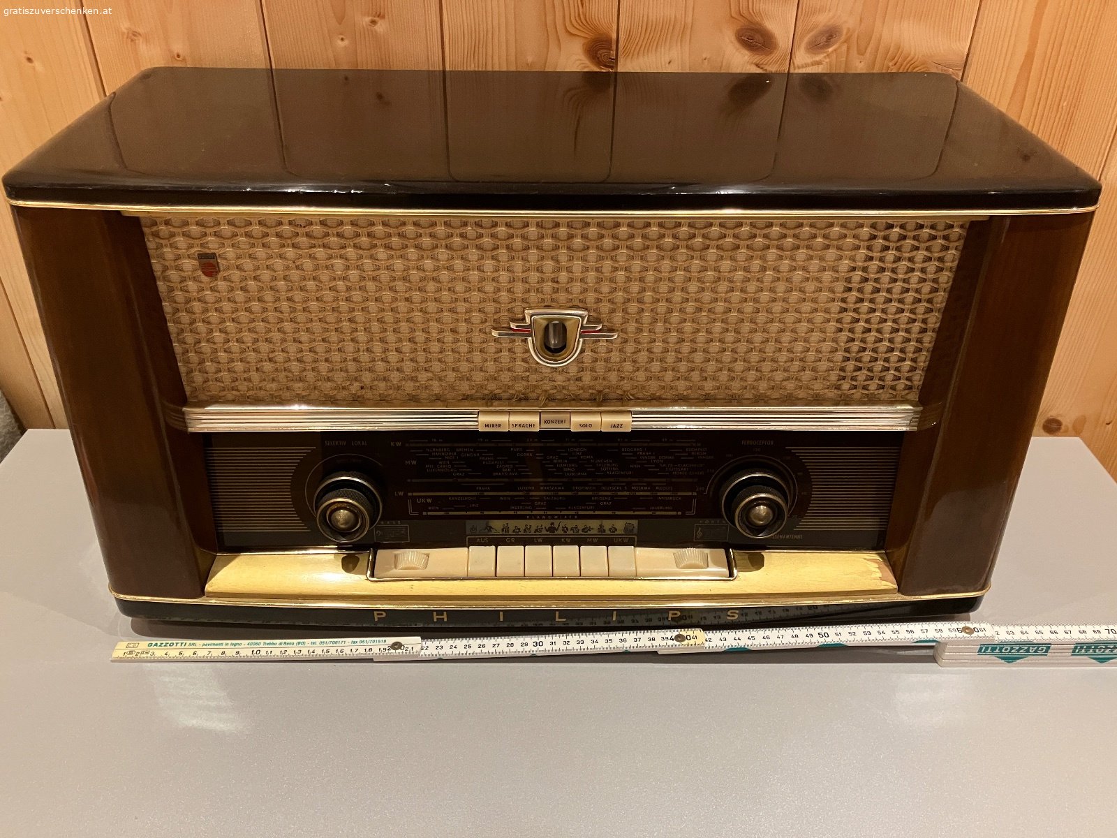 Alter Philips Röhrenradio / Vintage-Radio – funktionstüchtig. Verschenke einen alten Philips Radio im klassischen Holzgehäuse aus früheren Jahrzehnten.

Das Gerät ist funktionstüchtig und auch optisch für sein Alter noch in einem schönen Zustand. Ein dekoratives Stück für Liebhaber alter Radios, Sammler oder auch als Vintage-Dekoration.

Der Radio verfügt über die klassischen Wellenbereiche LW, KW, MW und UKW sowie verschiedene Klangtasten.

Der Lautstärkeregler sollte einmal gereinigt bzw. gewartet werden, ansonsten funktioniert das Gerät. Aufgrund des Alters wird es natürlich ohne Garantie auf dauerhafte Funktion abgegeben.

Abmessungen ca.:

* Breite: 60 cm
* Höhe: 38 cm
* Tiefe: 24 cm

Das schöne Holzgehäuse, die große Senderskala und die typische Stoffbespannung machen den Philips auch optisch zu einem schönen Zeitzeugen.

Gratis gegen Selbstabholung.
Vielleicht findet sich ein Liebhaber, der Freude daran hat und den Radio weiter verwendet oder restauriert.

Privatabgabe, keine Garantie oder Gewährleistung.