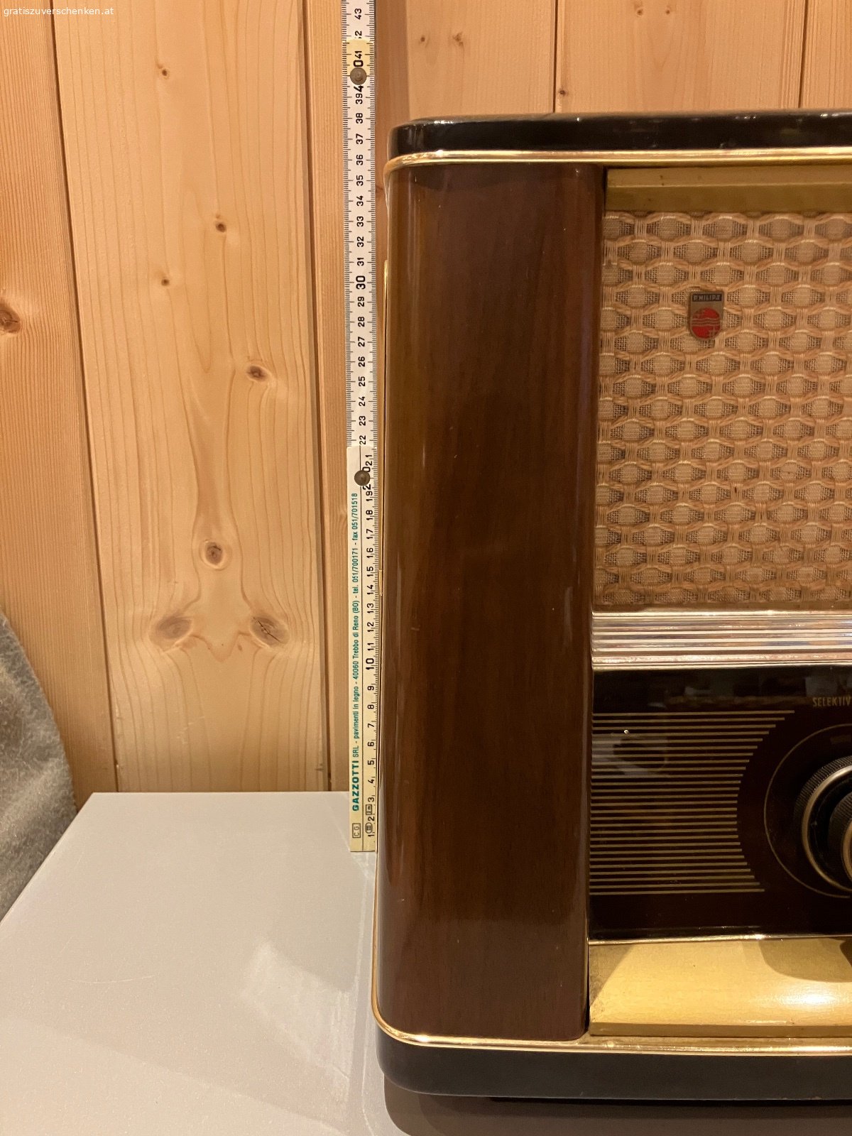Alter Philips Röhrenradio / Vintage-Radio – funktionstüchtig. Verschenke einen alten Philips Radio im klassischen Holzgehäuse aus früheren Jahrzehnten.

Das Gerät ist funktionstüchtig und auch optisch für sein Alter noch in einem schönen Zustand. Ein dekoratives Stück für Liebhaber alter Radios, Sammler oder auch als Vintage-Dekoration.

Der Radio verfügt über die klassischen Wellenbereiche LW, KW, MW und UKW sowie verschiedene Klangtasten.

Der Lautstärkeregler sollte einmal gereinigt bzw. gewartet werden, ansonsten funktioniert das Gerät. Aufgrund des Alters wird es natürlich ohne Garantie auf dauerhafte Funktion abgegeben.

Abmessungen ca.:

* Breite: 60 cm
* Höhe: 38 cm
* Tiefe: 24 cm

Das schöne Holzgehäuse, die große Senderskala und die typische Stoffbespannung machen den Philips auch optisch zu einem schönen Zeitzeugen.

Gratis gegen Selbstabholung.
Vielleicht findet sich ein Liebhaber, der Freude daran hat und den Radio weiter verwendet oder restauriert.

Privatabgabe, keine Garantie oder Gewährleistung.